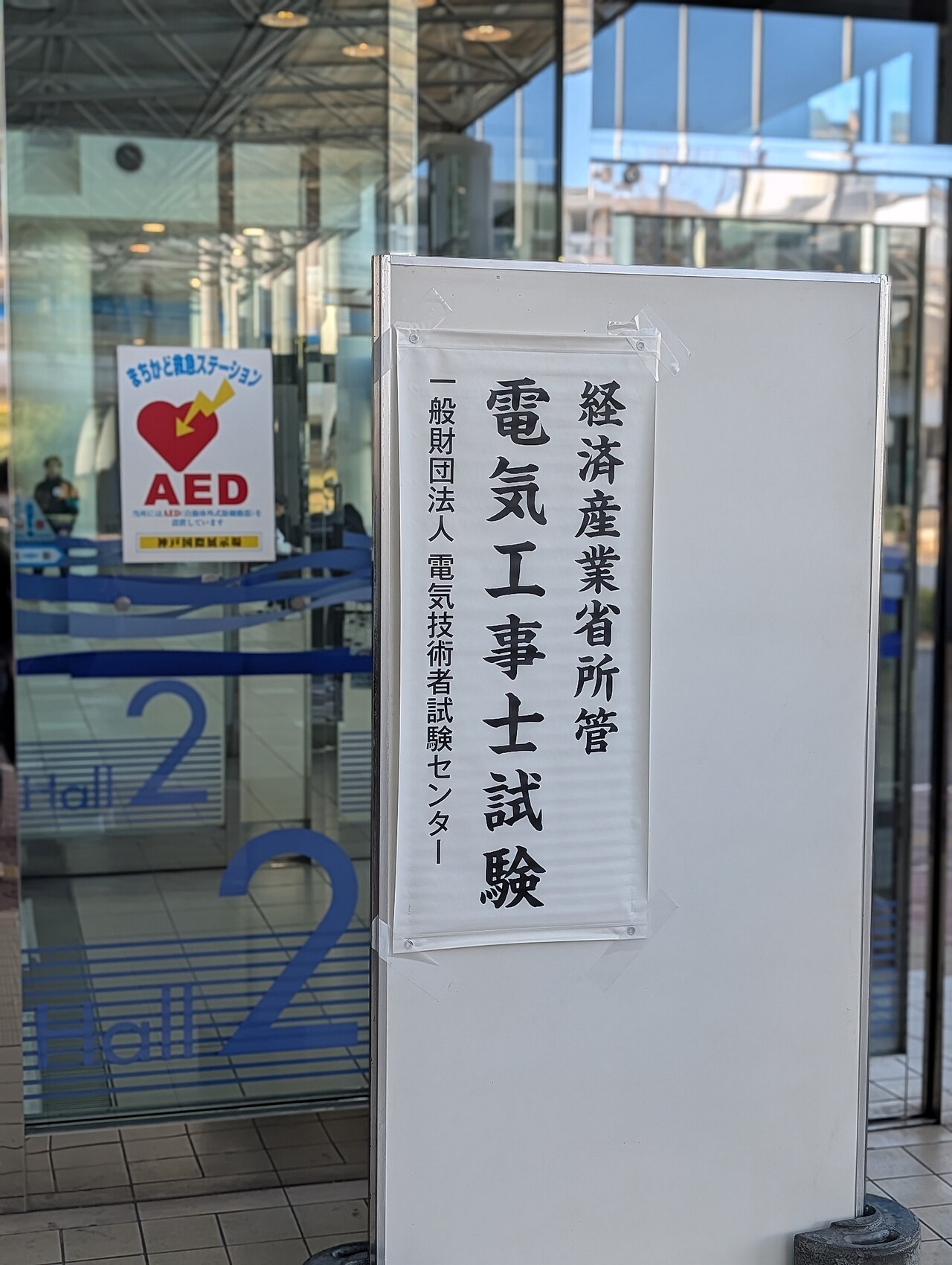A printed paper sign taped to a board at the entrance of an examination hall in Japan