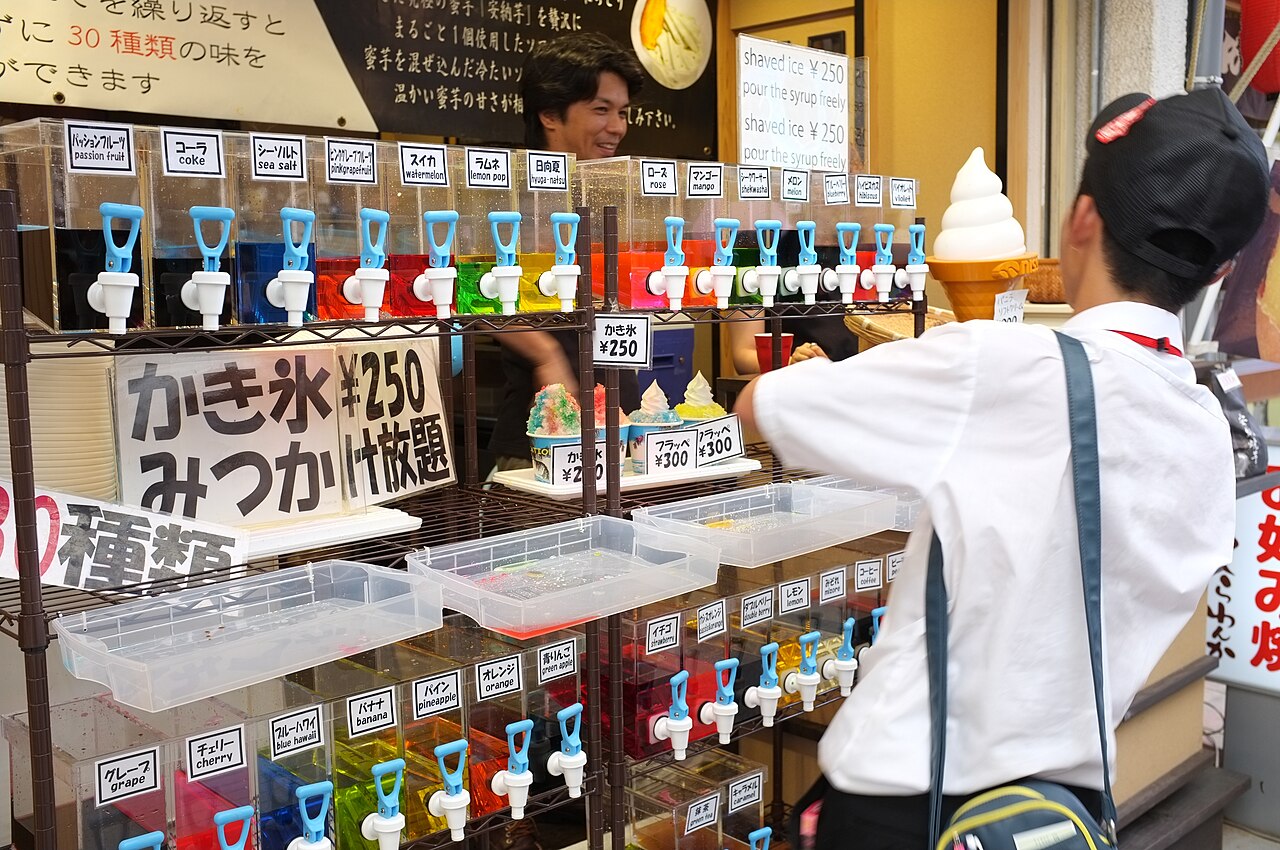 A kakigori stall with rows of coloured syrup bottles lined up along the counter